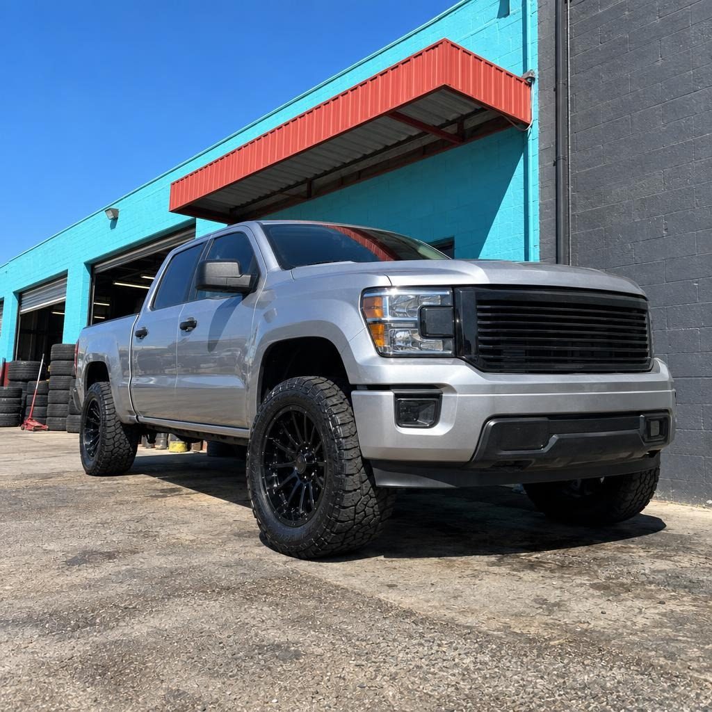 Silver pickup on new black wheels against the slate wall