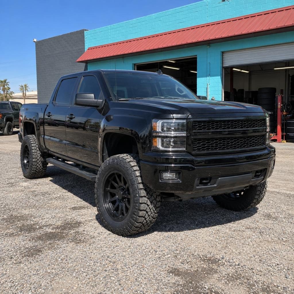 Black lifted pickup on black custom wheels in front of the shop