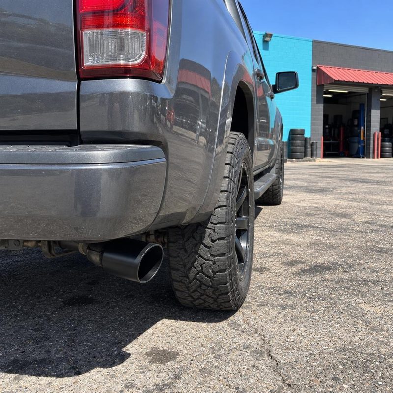 Exhaust tip under the rear of a gray pickup